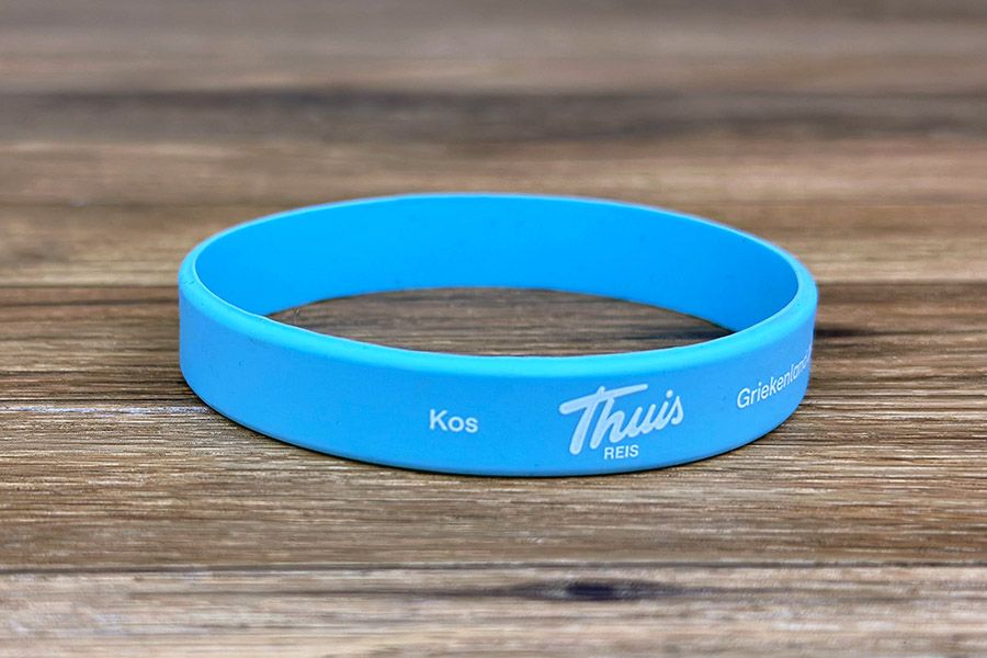 siliconen polsbandjes in licht blauw met witte bedrukking voor de VRT Thuis reis in 2026 naar Kos